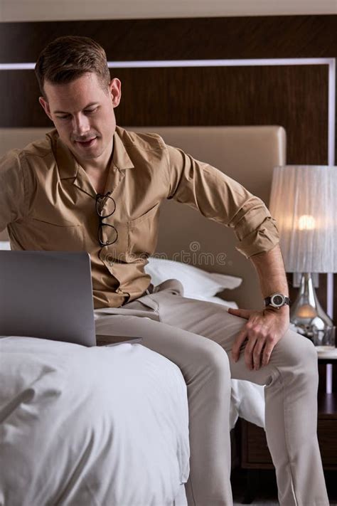 Young Handsome Guy Sit On Bed In Hotel Room Using Laptop Stock Image