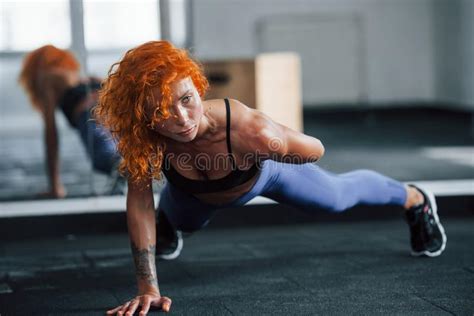 Showing Body While Holds Red Dumbbells Redhead Female Bodybuilder Is