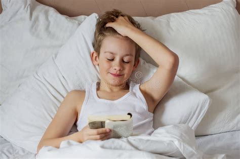 Teen Handsome Blonde Boy Lying In White Bed And Reading Book Relax