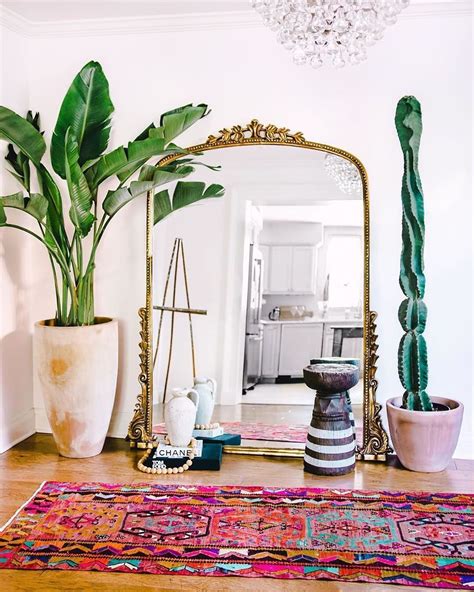 Lush Tropical Plants An Oversized Mirror And Colorful Area Rug Adorn
