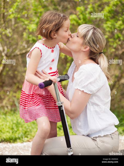 Madre e hija besándose en park con scooter Fotografía de stock Alamy