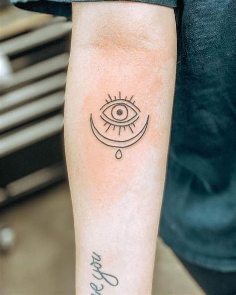 A Person With A Tattoo On Their Arm That Has An Evil Eye And The Word