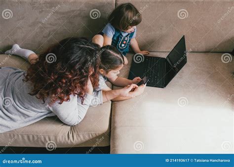 Mom With Two Young Daughters Lies On The Couch And Looks At The Phone Stock Image Image Of