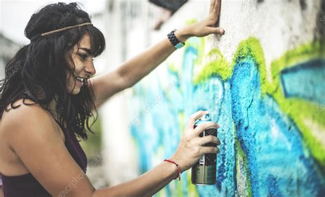 A Young Woman Spray Painting Graffiti Onto A Wall Stock Image F021