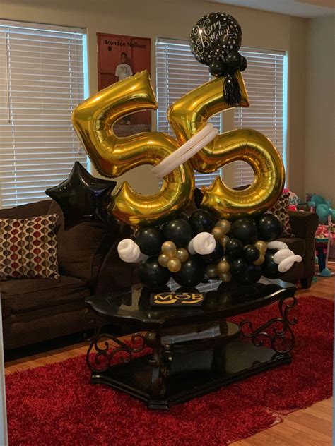 A Living Room Filled With Balloons And Black And Gold Decorations On