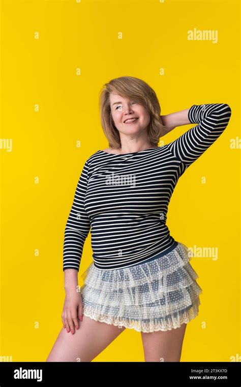 cheerful blondie woman 49 years in mini skirt and striped t shirt posing with hand behind head