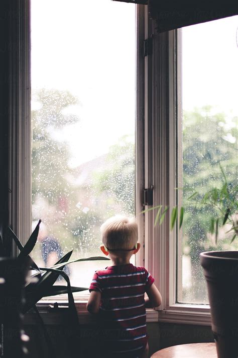 Little Boy Looking Out The Window On A Rainy Day Del Colaborador De