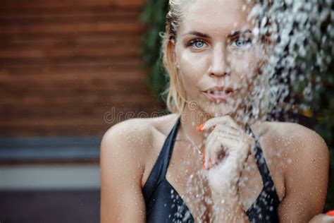 shooting in the aquazone with falling water drops a girl with blond hair in a black swimsuit