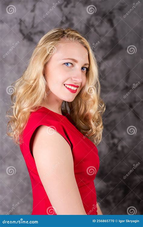 Portrait Of A Pretty Blonde In A Red Dress On A Gray Marble Background