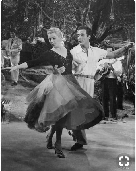 An Old Black And White Photo Of A Man And Woman Dancing In Front Of