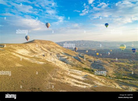 Hot Air Balloons Fly Over A Mountain In Cappadocia Turkey Stock Photo