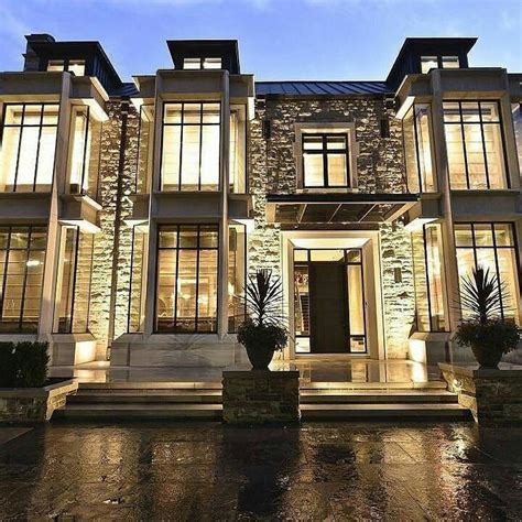 A Large House With Lots Of Windows And Lights On Its Front Entrance At