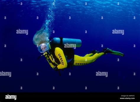 Blonde Woman Wearing A Yellow Wet Suit Scuba Diving In The Blue Sea