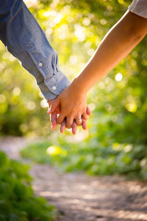 Close Up Of Couples Interlaced Hands On A Trail In Afternoon