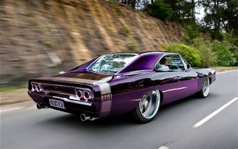 A Purple Muscle Car Driving Down The Road