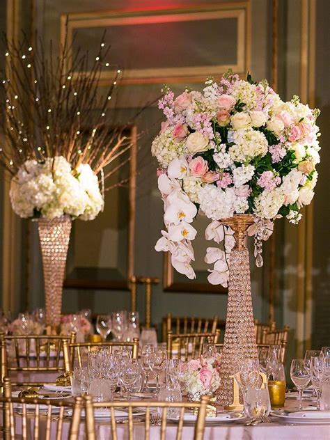 Tall Vases Filled With White And Pink Flowers On Top Of A Table Covered