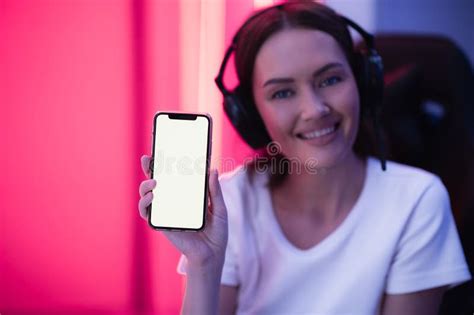 Happy Gamer Girl Wearing Headset Showing Smart Phone Display And