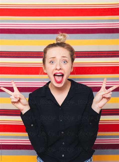 Portrait Of A Woman Making Funny Faces In Front Of A Striped Wall By