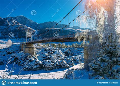 Big Road Bridge Over Frozen River Against A Backdrop Of Snow Capped