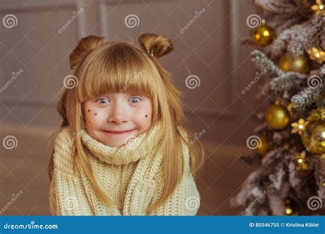Portrait Of A Charming Little Girl In Beige Sweater Makes Faces In