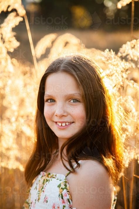 Image Of Young Tween Girl And Bulrushes Backlit By Golden Sunlight