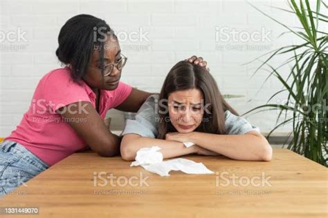 Two Young Women Of Mixed Race Lesbian Couple Sitting In Their Home And
