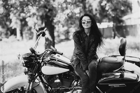 Sexy Biker Woman In A Leather Jacket And Sunglasses Is Sitting On Her