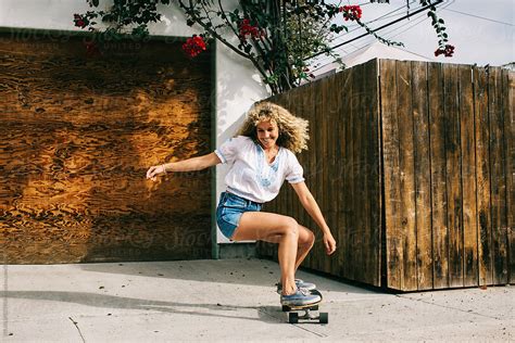 Beautiful Young Curly Woman Skateboarding On Venice Sidewalk With Big