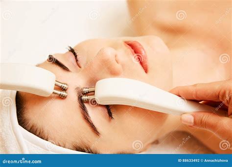 Cosmetology Beautiful Woman At Spa Clinic Receiving Stimulating Electric Facial Treatment From