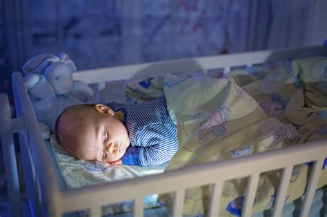 Adorable Newborn Baby Boy Sleeping In Crib At Night Stock Photo