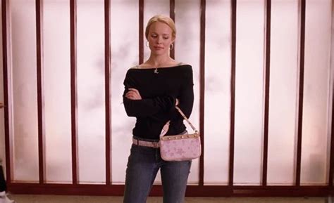 A Woman Standing In Front Of A Wall Holding A Pink Purse