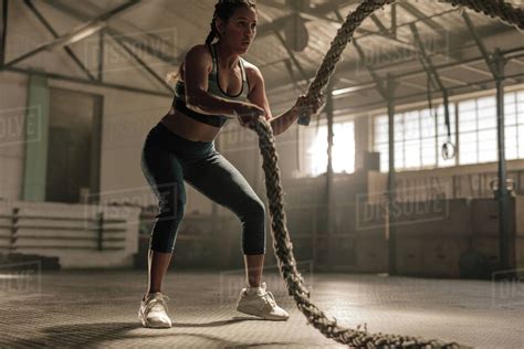 Young Woman Doing Strength Training Using Battle Ropes At The Gym