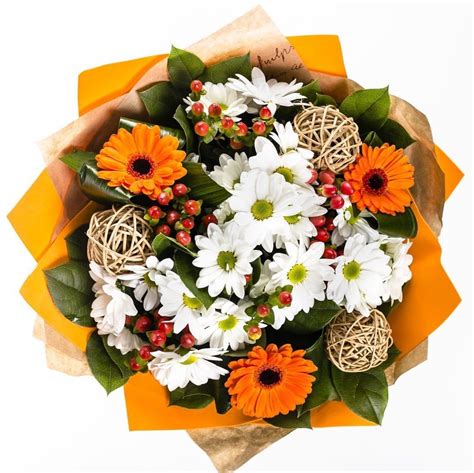 A Bouquet Of White And Orange Flowers On Top Of An Orange Wrapper With