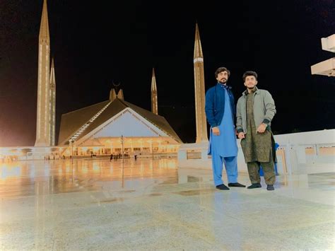 Two Men Standing Next To Each Other In Front Of A Building With Tall Spires