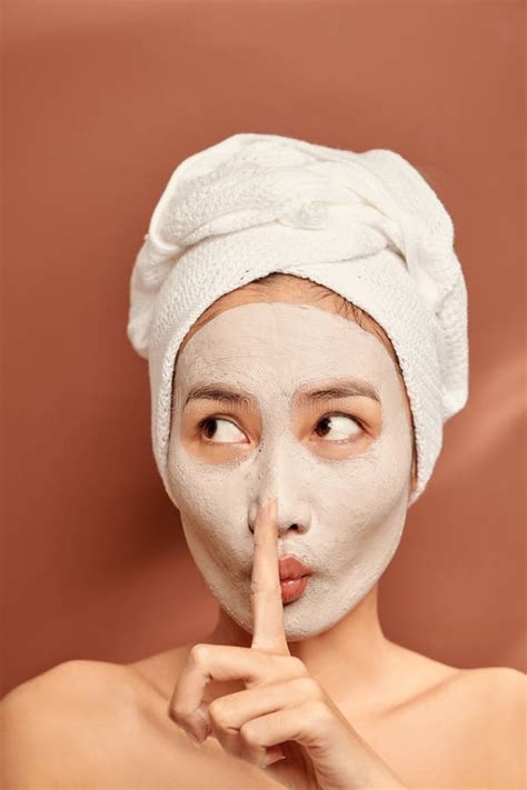 Beautiful Woman With Clay Facial Mask Over Orange Background Beauty Treatment And Spa Concept