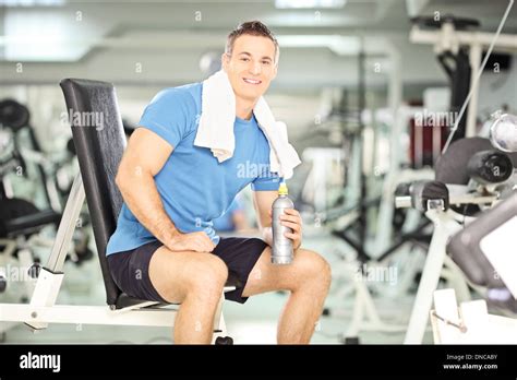 Smiling Man Seated On A Bench Drinking Water After Exercise In Fitness