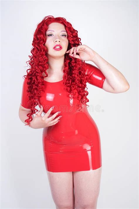 Hot Sexual Redheaded Girl With Plus Size Body Wears Fashion Latex Rubber Red Dress And Posing On