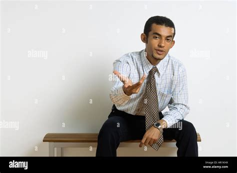Young Man Sitting Asking A Question With Hand Gesture Stock Photo Alamy