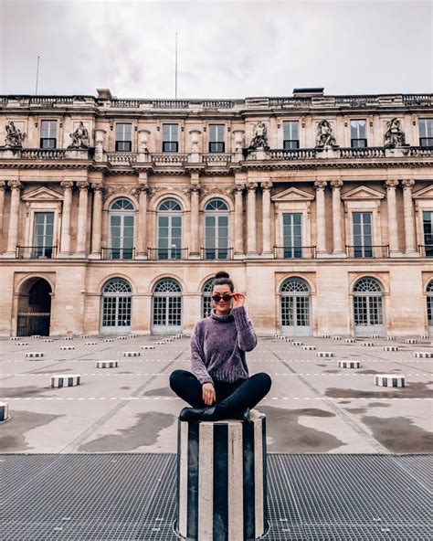 A Man Sitting On Top Of A Metal Box In Front Of A Large Stone Building