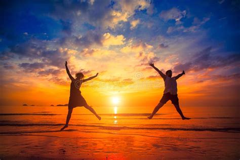 Silhouettes Of Young People Jumping At Sunset On The Sea Beach Happy