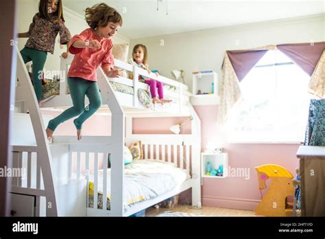Young Girls Having Fun Playing Jumping Off Bunk Bed In Bedroom Stock
