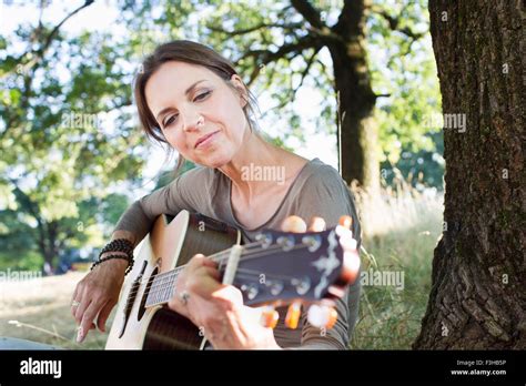 Mature Woman Playing Acoustic Guitar In Park Stock Photo Alamy