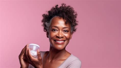 Premium Ai Image Black Mature Older Woman Smiling Holding Blank Cream Jar Product Display Pink