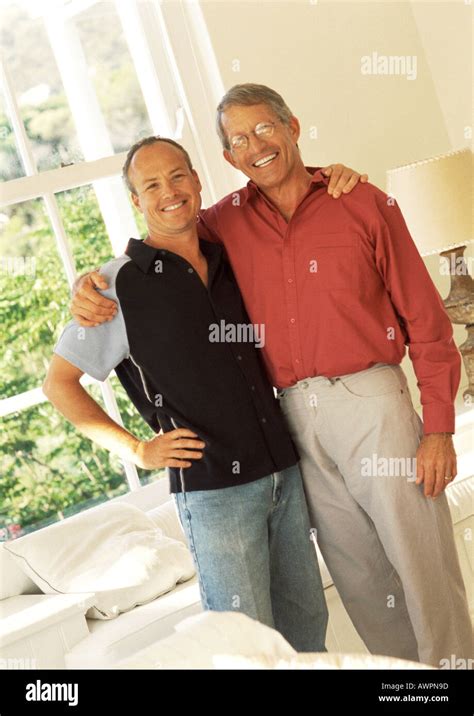 Two Men Standing Side By Side With Arms Around Each Other Smiling