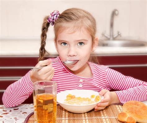 Cute Smiling Little Girl Having Breakfast Cereals With Milk Stock Photo