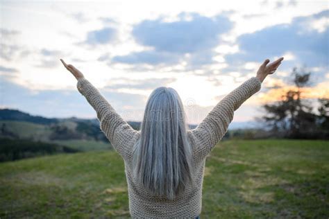 Rear View Of Senior Woman With Arms Outstretched And Face Up At Park On Spring Day Stock Image