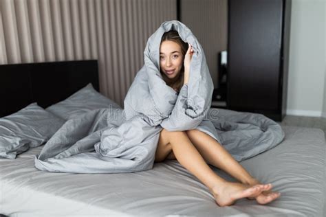 Smiling Woman Under A Duvet Sitting In Her Bedroom Stock Image Image
