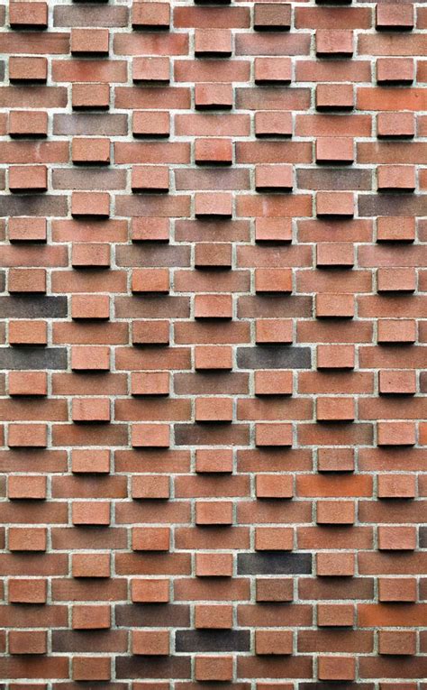 A Brick Wall That Is Made Out Of Red Bricks And Has Small Black Squares