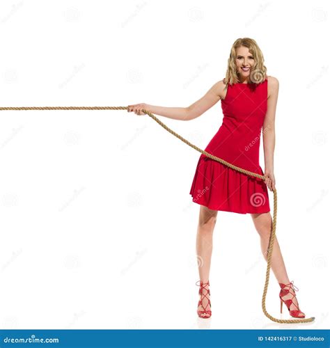 Smiling Young Woman In Red Dress And High Heels Is Pulling The Rope