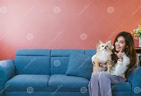 Portrait Of Young Asian Woman Holding Her Dog Chihuahua On Sofa At Home